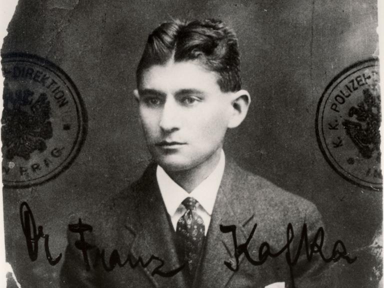 Ein schwarzweißes Passfoto zeigt Franz Kafka, der sehr ernst blickt