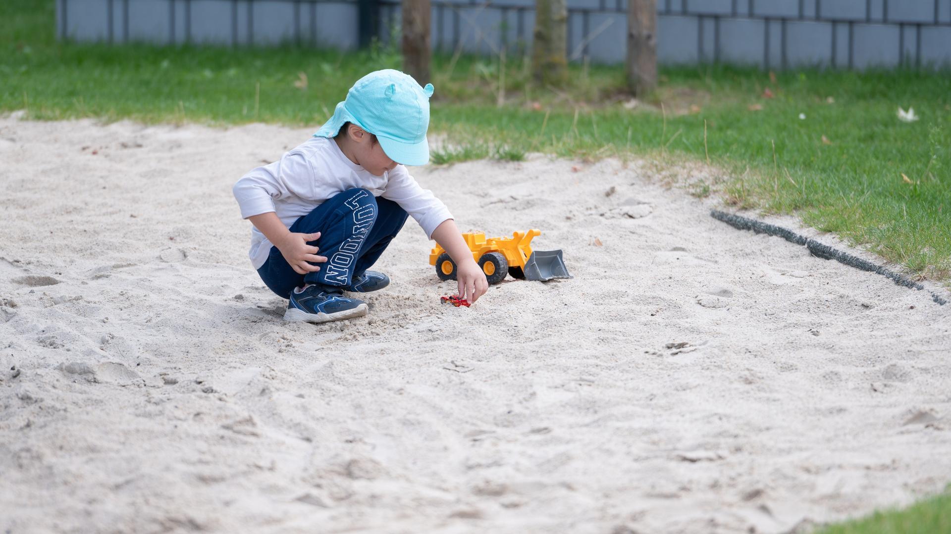 Ein Kind spielt im Sandkasten.