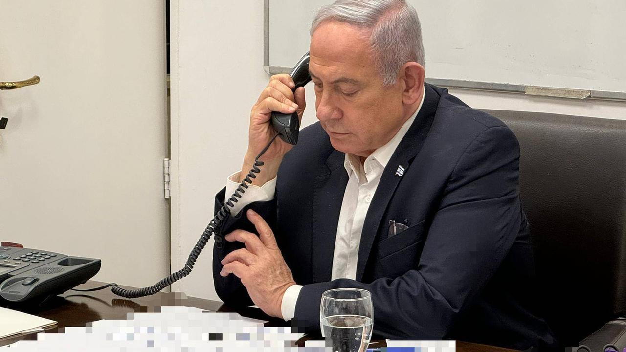 Israels Premier Benjamin Netanjahu am Telefon, verpixelte Dokumente vor sich auf dem Tisch