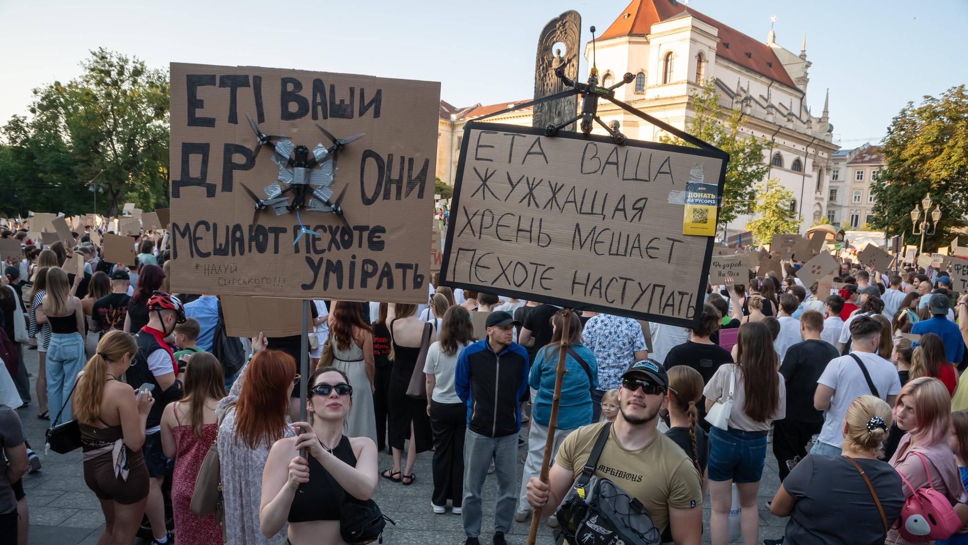 Menschen protestieren in Kiew gegen die Entlassung des ukrainischen Verteidigungsministers Fedorow. Sie halten Pappschilder hoch. Darauf sind Forderungen in ukrainischer Sprache zu lesen.