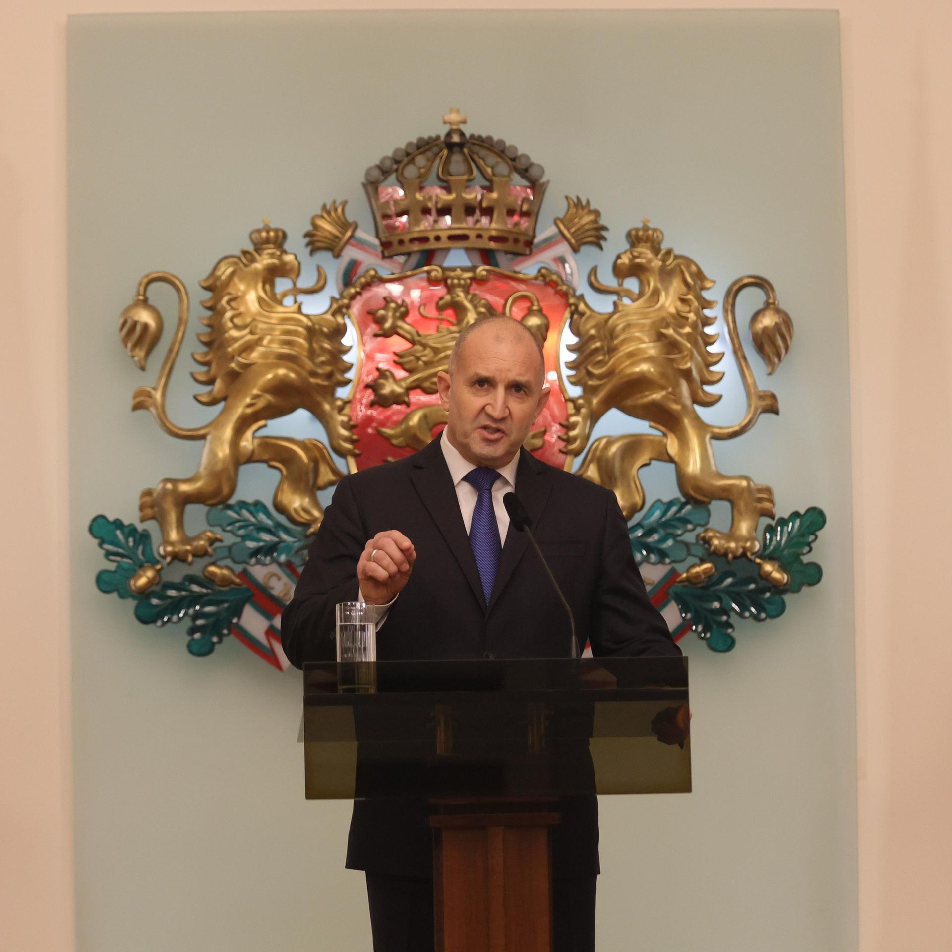 Bulgariens Präsident Rumen Radew kündigt seinen Rücktritt vom Amt des Staatspräsidenten an. Dabei steht er an einem Rednerpult, zu seiner linken Seite eine Europa-Flagge, zu seiner rechten Seite eine bulgarische.