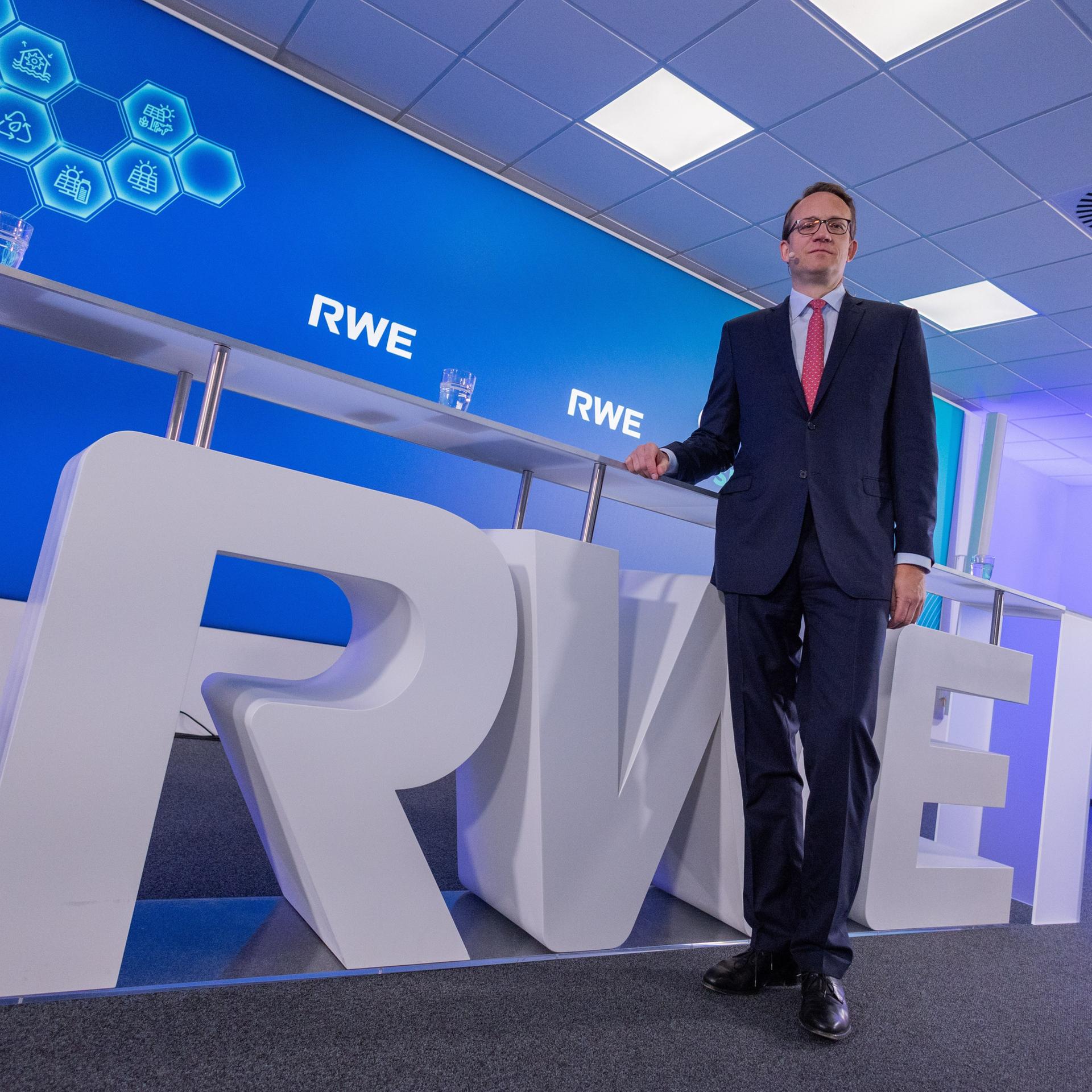 Markus Krebber, Vorstandsvorsitzender der RWE AG, spricht bei der Bilanzpressekonferenz. Er stützt sich auf eine Theke, die aus den Buchstaben RWE besteht.