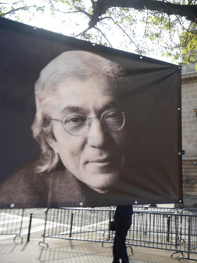 Auf der Straße protestiert ein Mann mit einem Banner für die Freilassung von Boualem Sansal, links daneben ein Plakat, das den franko-algerischen Schriftsteller zeigt.
