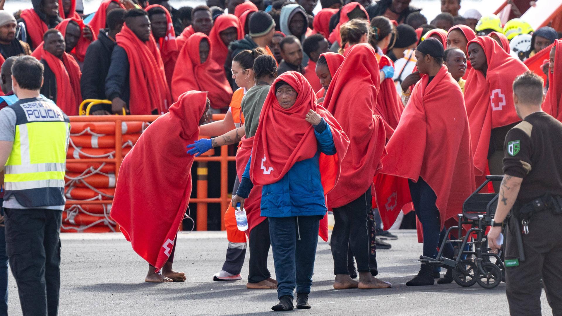 Ein Gruppe Flüchtlinge, eingehüllt in roten Decken, erreicht Arrecife auf Lanzarote.