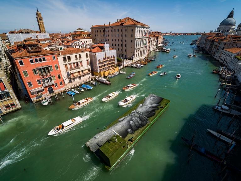 Luftbild vom Landart-Gemälde in der Lagune von Venedig: Zu sehen sind zwei verschränkte Riesenhände.