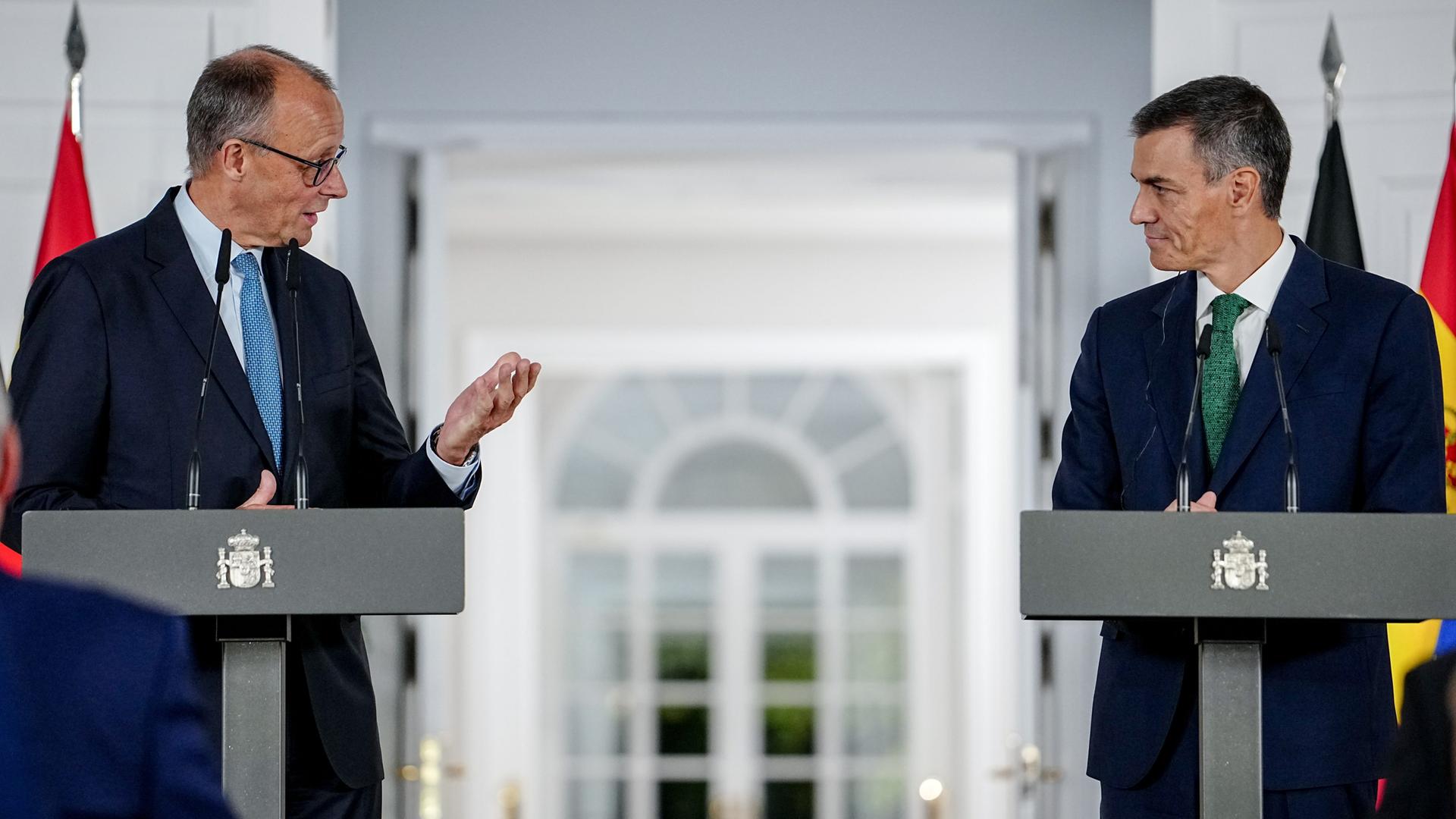 Bundeskanzler Friedrich Merz und Pedro Sánchez, Ministerpräsident von Spanien, geben eine Pressekonferenz. Beide Politiker stehen vor Stehpulten. Merz und Sanchez schauen sich gegenseitig an.