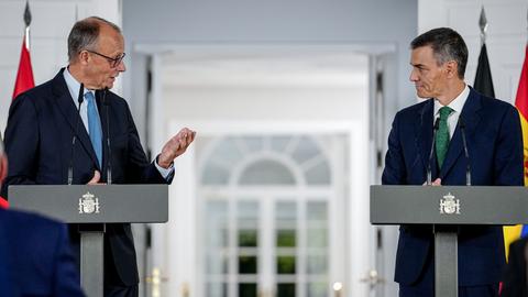 Bundeskanzler Friedrich Merz und Pedro Sánchez, Ministerpräsident von Spanien, geben eine Pressekonferenz. Beide Politiker stehen vor Stehpulten. Merz und Sanchez schauen sich gegenseitig an.