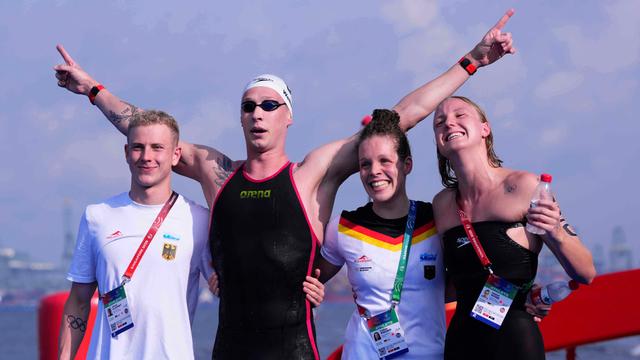 Florian Wellbrock freut sich über seine 4. Gold-Medaille mit der Staffel. Neben ihm stehen die Schwimmer Oliver Klemet (links) Isabel Gose und Celine Rieder. Er hat noch seine Schwimmbrille auf. 
