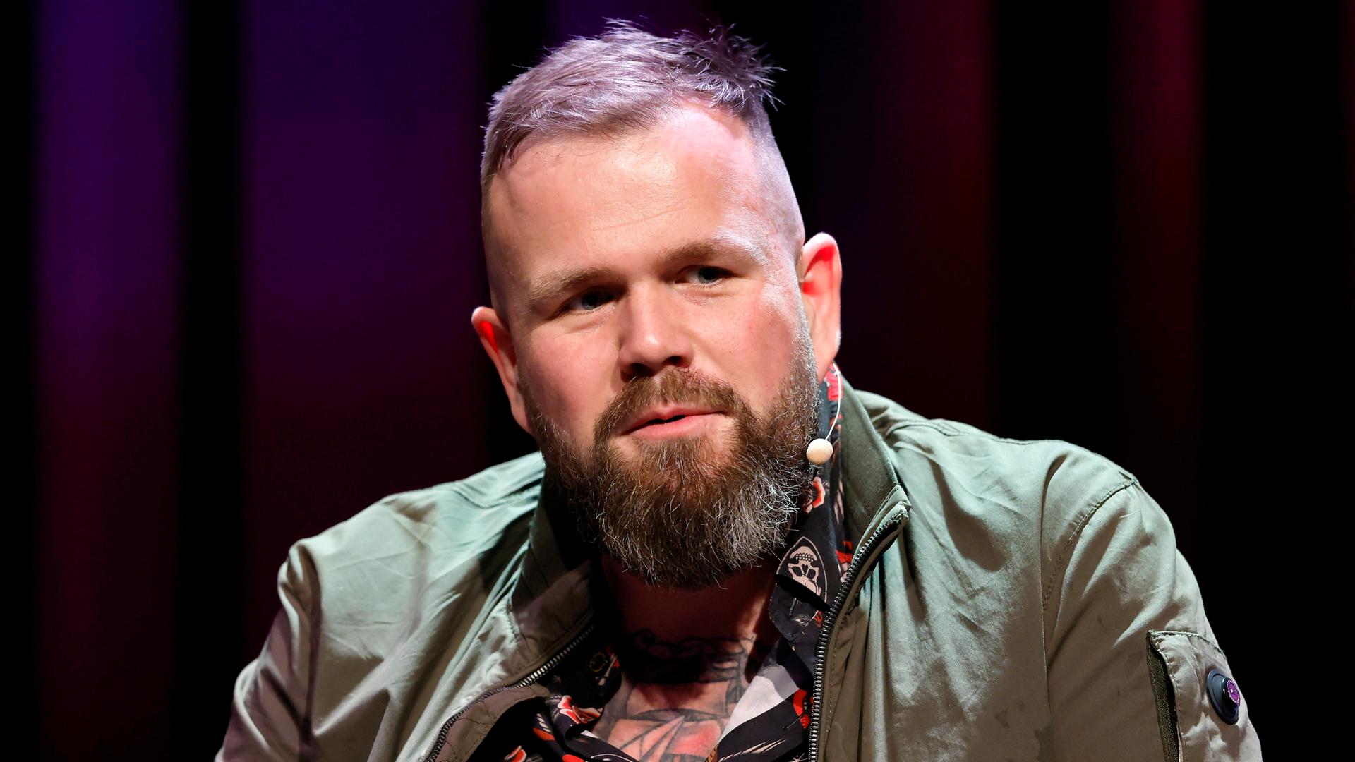 Sänger Jan Gorkow von der Band Feine Sahne Fischfilet sitzt bei einer Veranstaltung im Rahmen der Lit.Cologne 2026 im Theater am Tanzbrunnen vor einem dunklen Hintergrund auf der Bühne. 