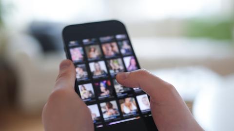 Ein junger Mann schaut sich auf einem Smartphone eine Porno-Internetseite an (gestellte Szene).