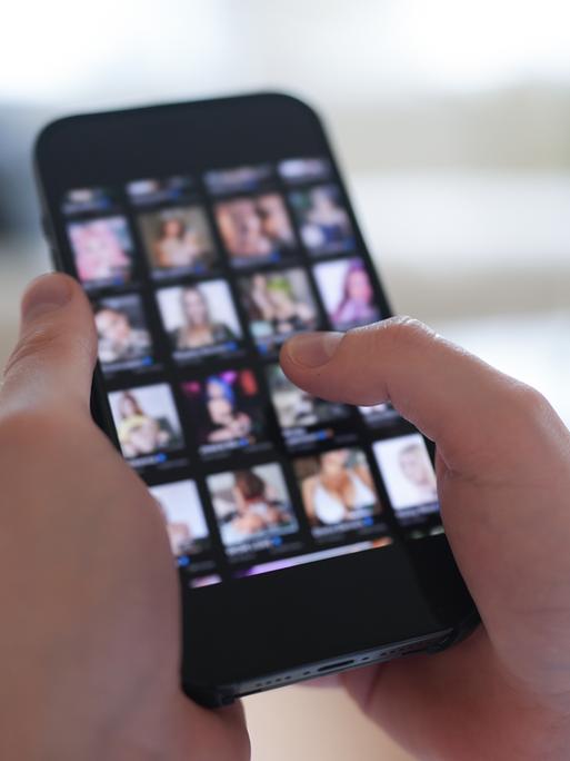 Ein junger Mann schaut sich auf einem Smartphone eine Porno-Internetseite an (gestellte Szene).