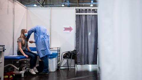 Eine Frau sitzt in einer Impfkabine im Impfzentrum in Essen und bekommt den Impfstoff von Biontech/Pfizer gespritzt. 