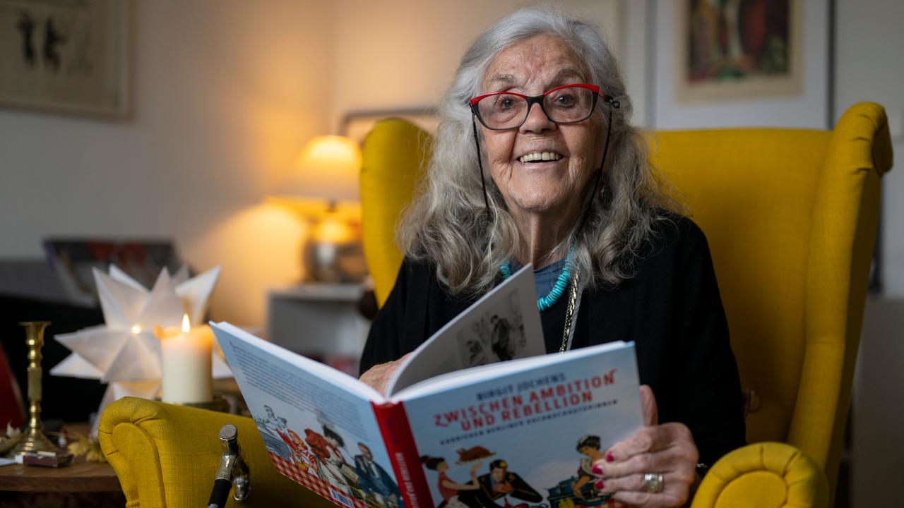 Ursula Winnington, Kochbuchautorin und Köchin, sitzt in einem Sessel und hält ein Kochbuch in den Händen. 