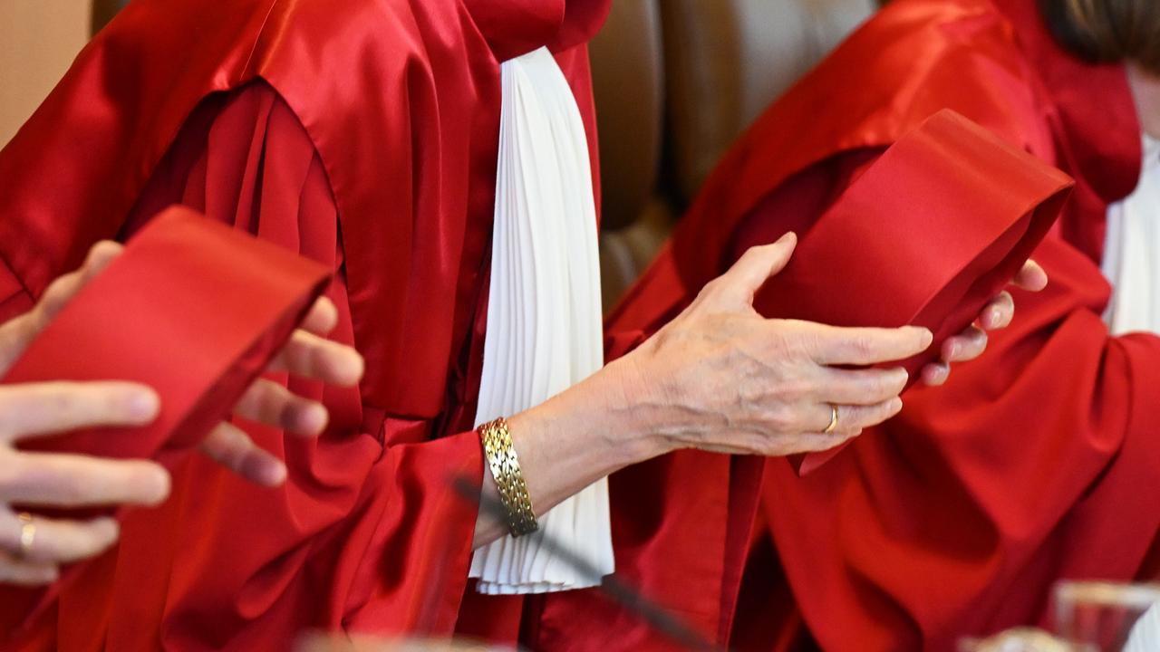 Richterinnen und Richter im zweite Senat des Bundesverfassungsgerichts tragen in roten Roben halten ihre Hüte in den Händen.