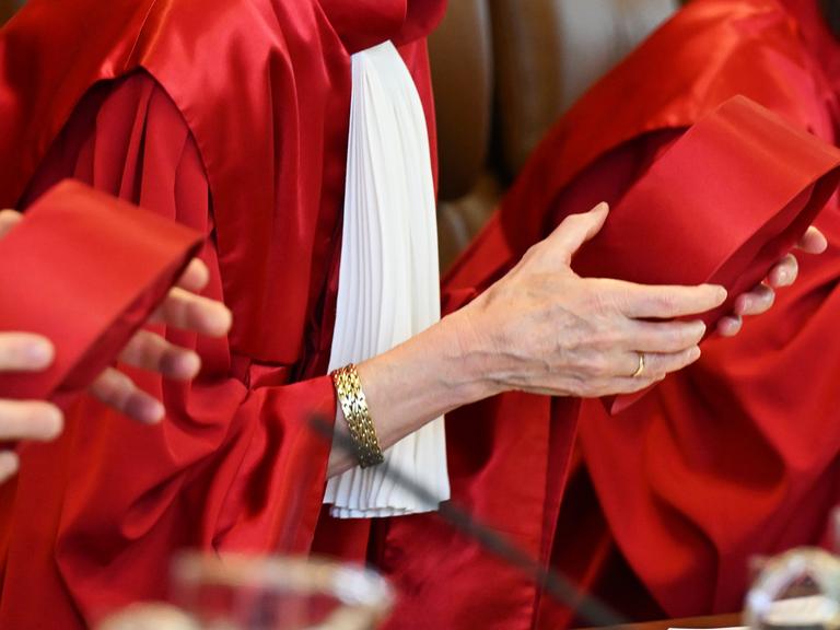 Richterinnen und Richter im zweiten Senat des Bundesverfassungsgerichts tragen rote Roben und halten ihre Hüte in den Händen. 