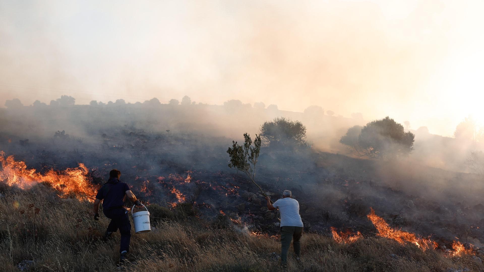 Menschen versuchen den Brand auf der griechischen Insel Chios zu löschen. Menschen versuchen den Brand auf der griechischen Insel Chios zu löschen.
