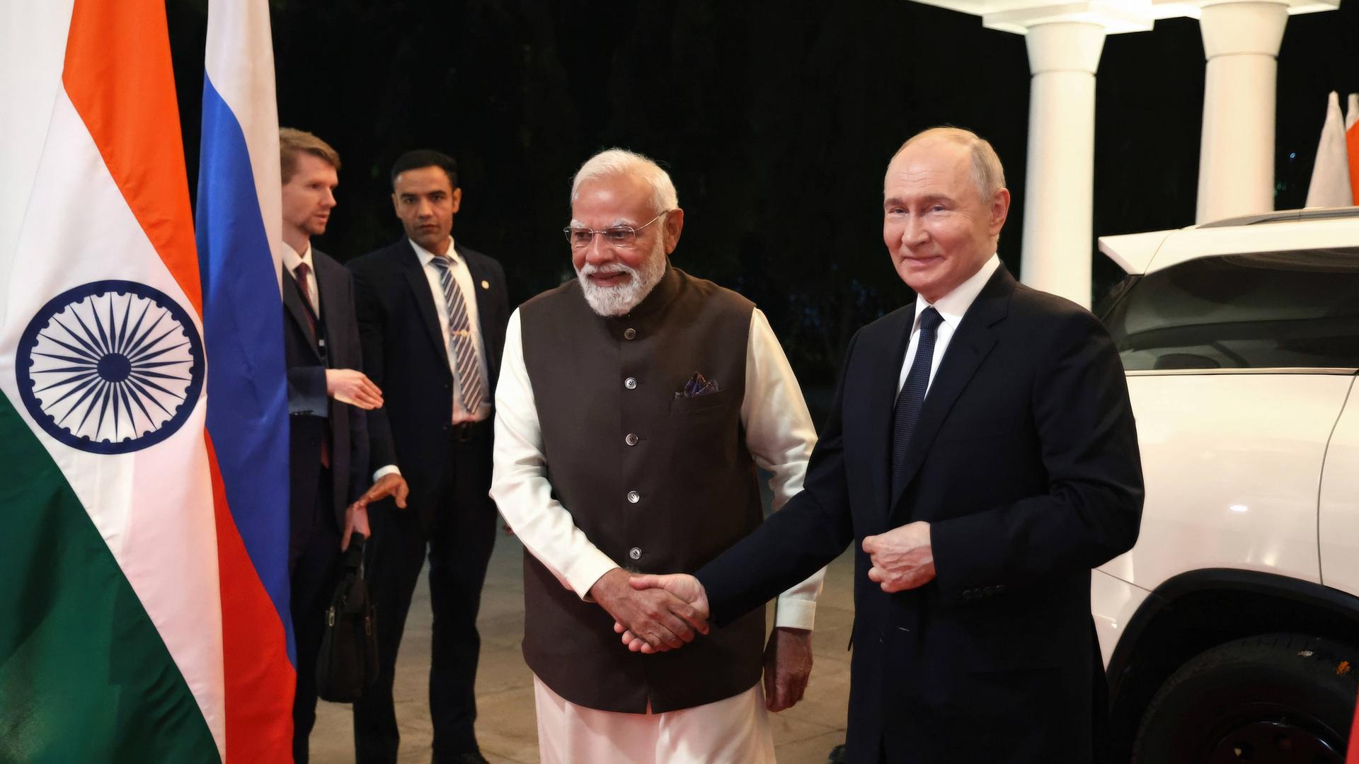 Putin und Modi schütteln sich mit Händeschütteln. Sie stehen nebeneinander und lächeln in Richtung der Kamera. Putin und Modi schütteln sich mit Händeschütteln. Sie stehen nebeneinander und lächeln in Richtung der Kamera.