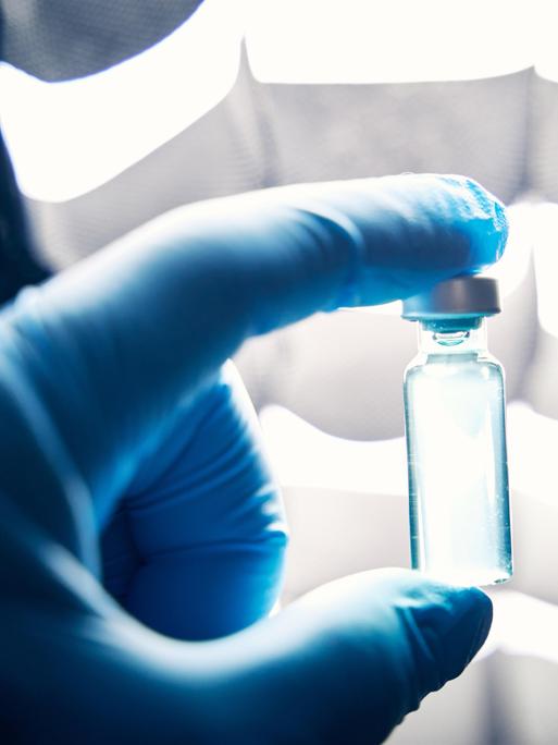 Ein Arzt hält mit Schutzhandschuhen in einem Labor eine Ampulle mit einem Impfstoff (Symbolbild). Ein Arzt hält mit Schutzhandschuhen in einem Labor eine Ampulle mit einem Impfstoff (Symbolbild).