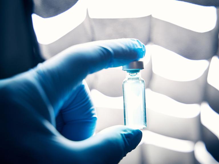 Ein Arzt hält mit Schutzhandschuhen in einem Labor eine Ampulle mit einem Impfstoff (Symbolbild). Ein Arzt hält mit Schutzhandschuhen in einem Labor eine Ampulle mit einem Impfstoff (Symbolbild).