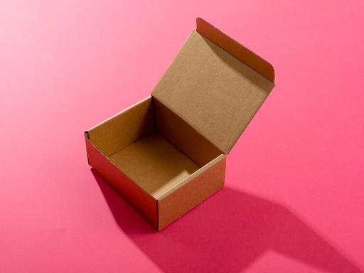 Eine leere geöffnete Schachtel aus Karton auf einem roten Hintergrund.
