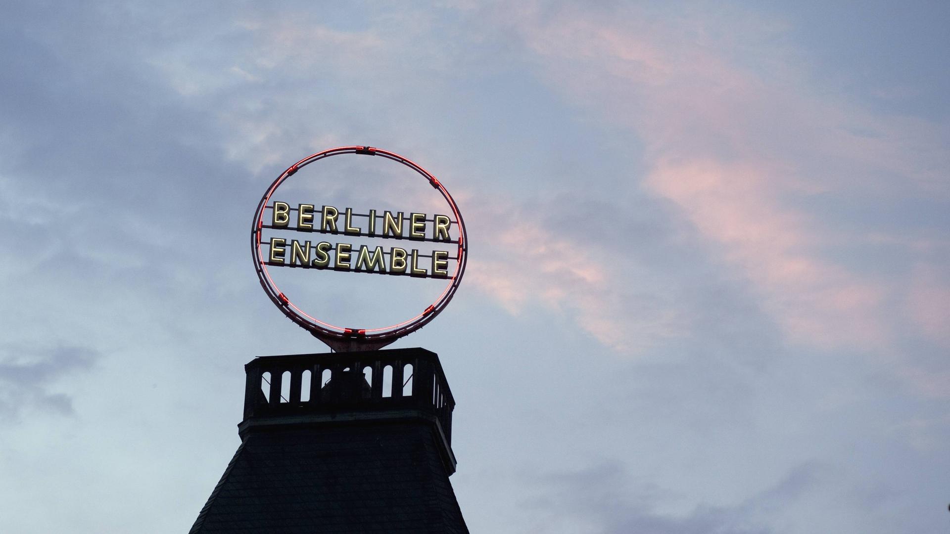 Auf dem Dach des Berliner Ensembles leuchtet das Logo in der Abenddämmerung.