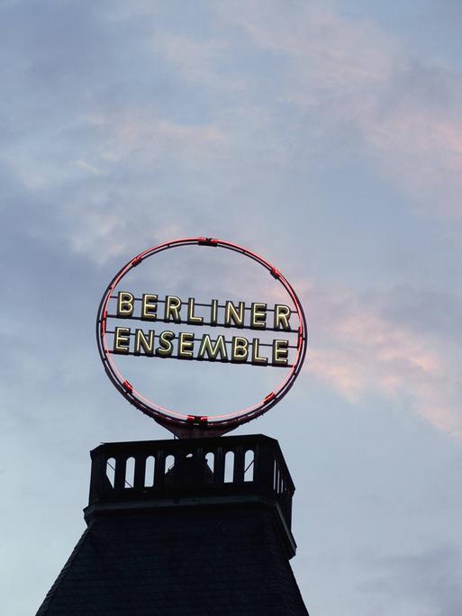 Auf dem Dach des Berliner Ensembles leuchtet das Logo in der Abenddämmerung.