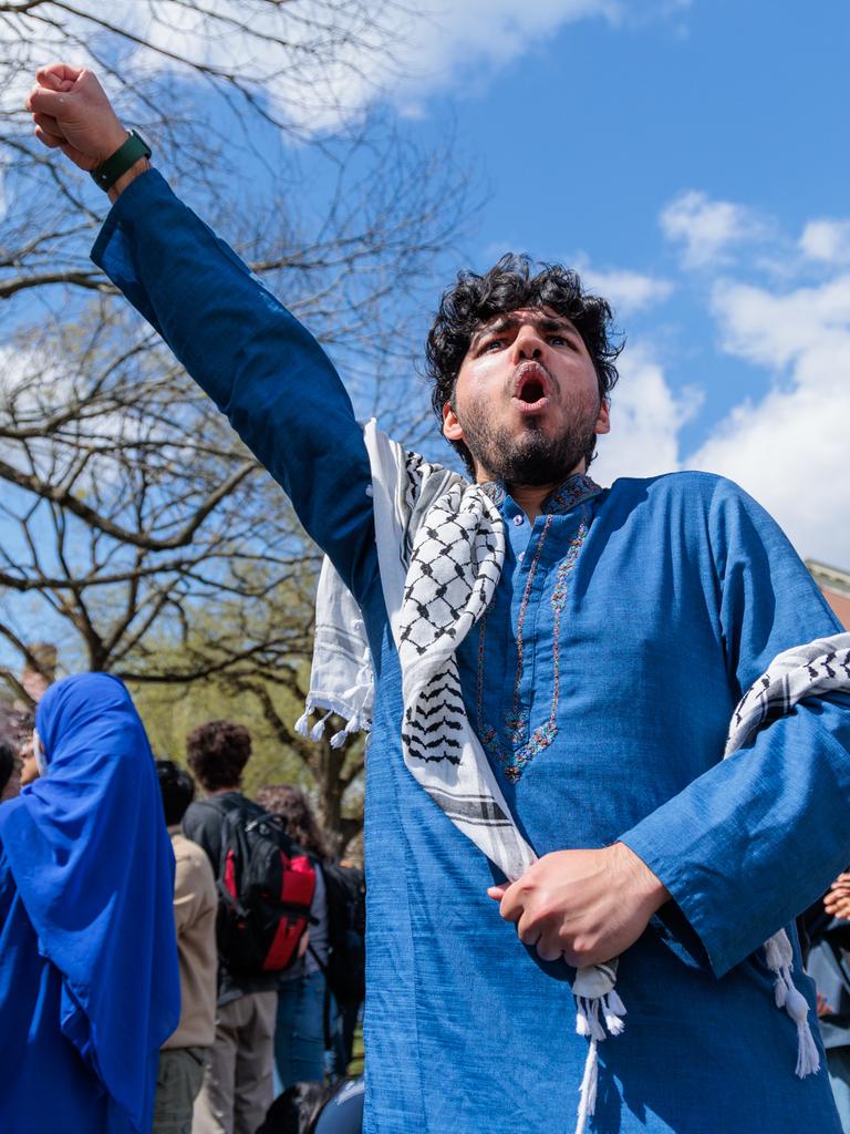 Ein junger Mann mit umgebundenen Palästinensertuch reckt die Faust im Protest in die Luft.
