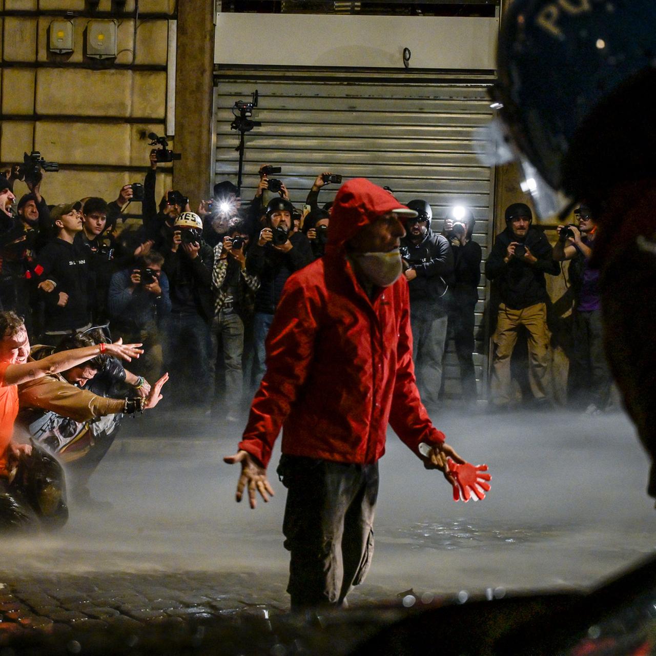 Demonstration in Rom: Ein Mann steht einer Gruppe von Polizisten gegenüber. Er gestikuliert. Hinter ihm stehen weitere Menschen.