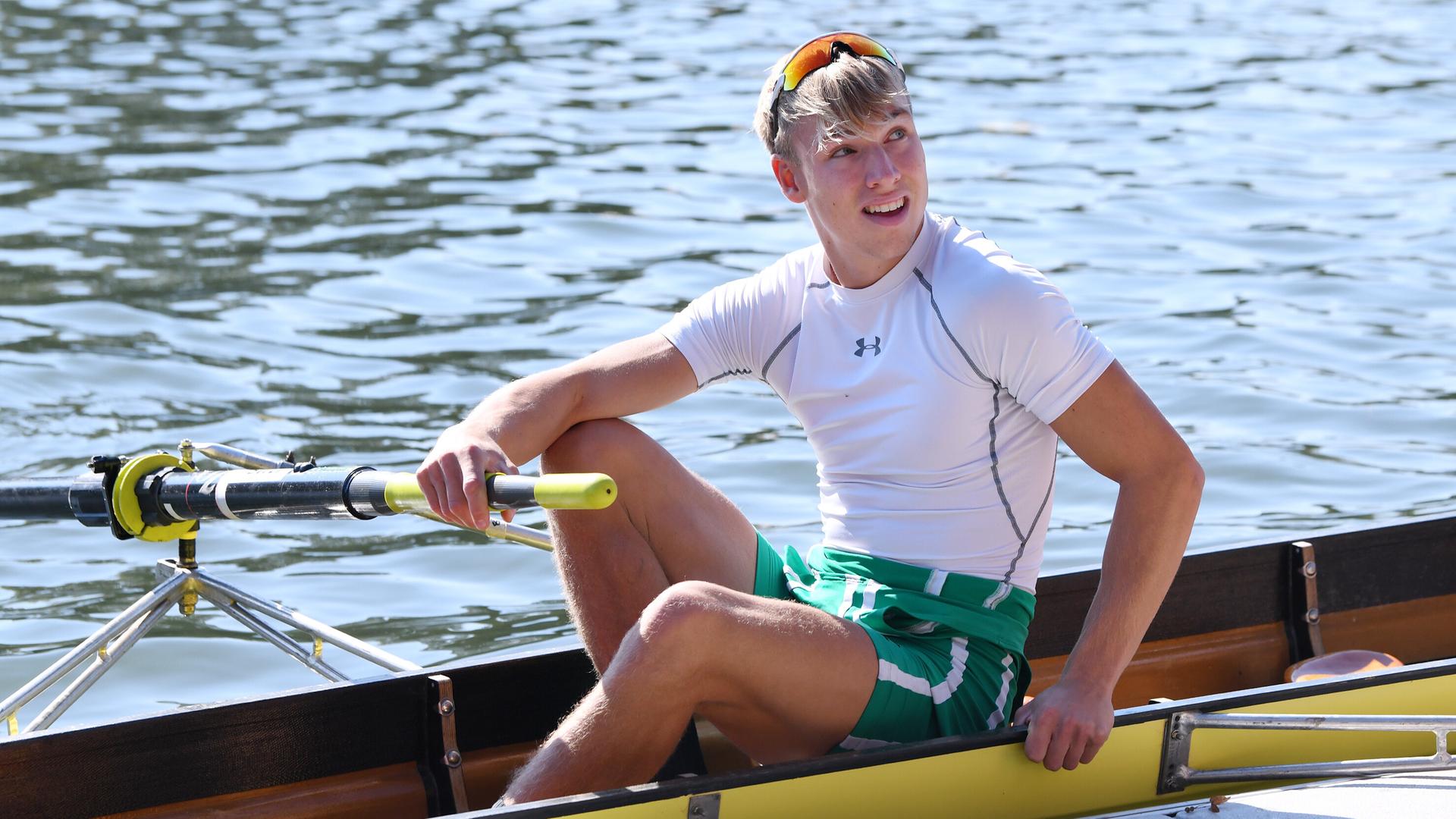 Ein Mann sitzt in einem Sport-Ruderboot und schaut zur Seite. Ein Mann sitzt in einem Sport-Ruderboot und schaut zur Seite.