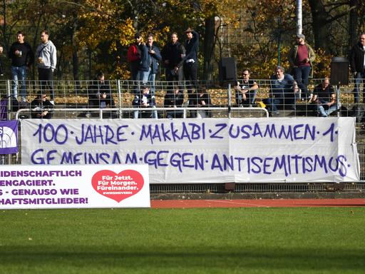 Ein Banner mit der Aufschrift "100 Jahre Makkabi - zusammen - gemeinsam gegen Antisemitismus" hängt in einem Fußballstadion.