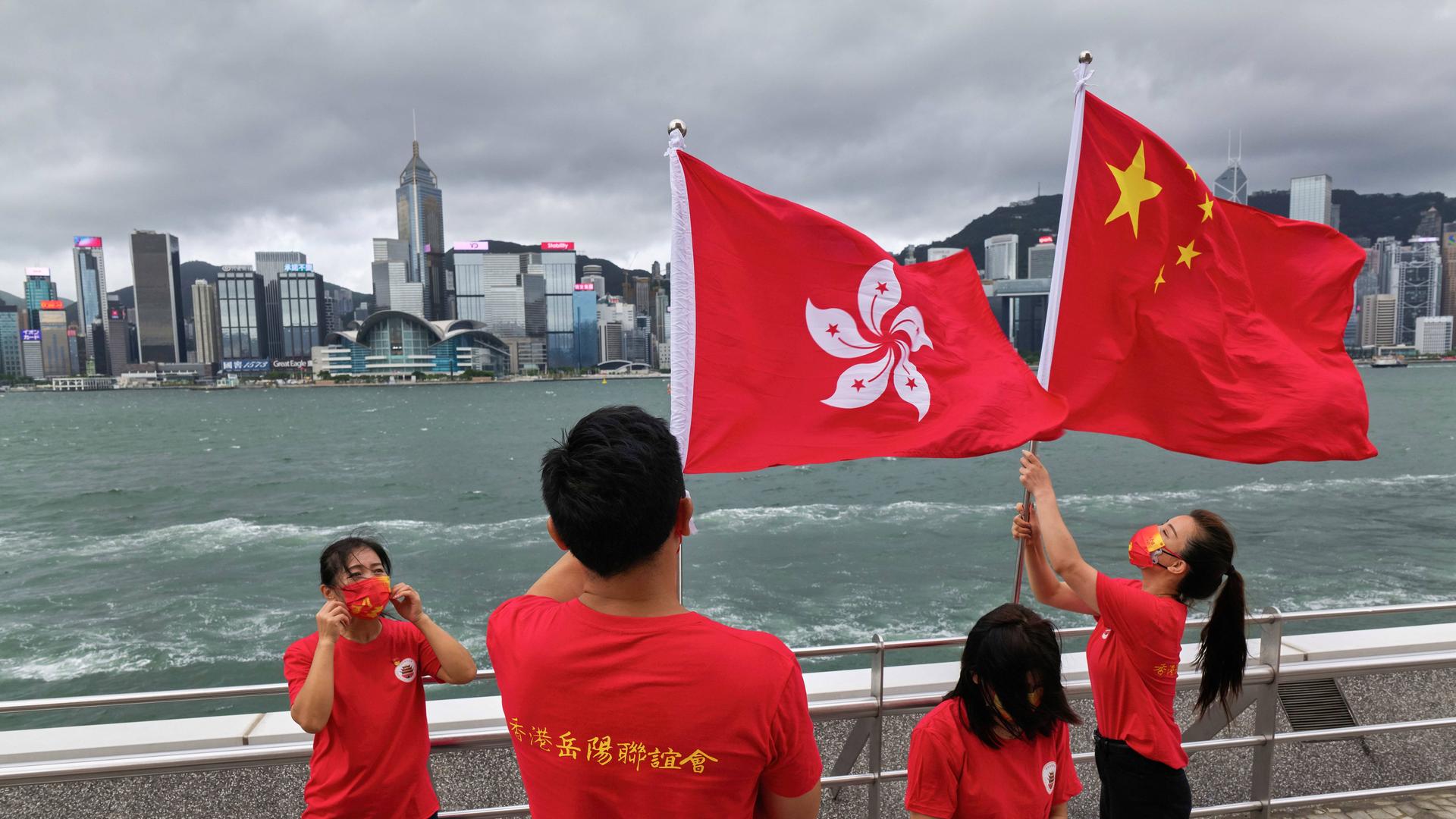 Menschen machen Fotos mit chinesischen und Hongkong-Flaggen vor der Bucht von Hongkong während der Jubiläumsfeierlichkeiten. 