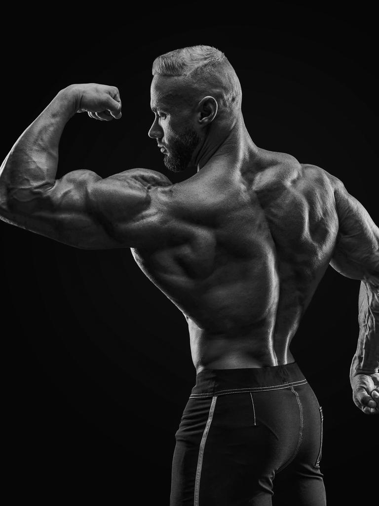 Silhouette eines kräftigen Bodybuilders, der die Muskeln seines linken Oberarms anspannt.