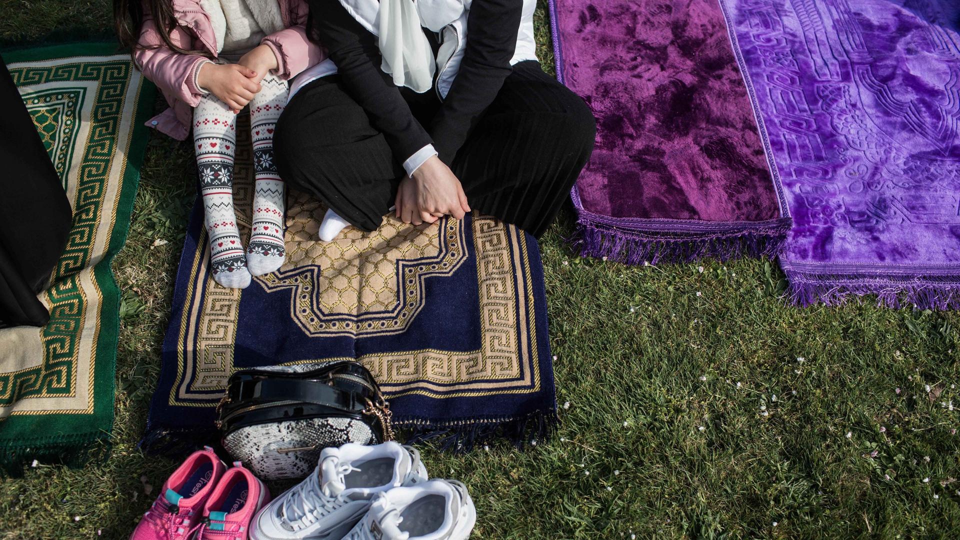 Eine Frau und ein Kind sitzen beim Fest des Fastenbrechens auf einem Gebetsteppich. 