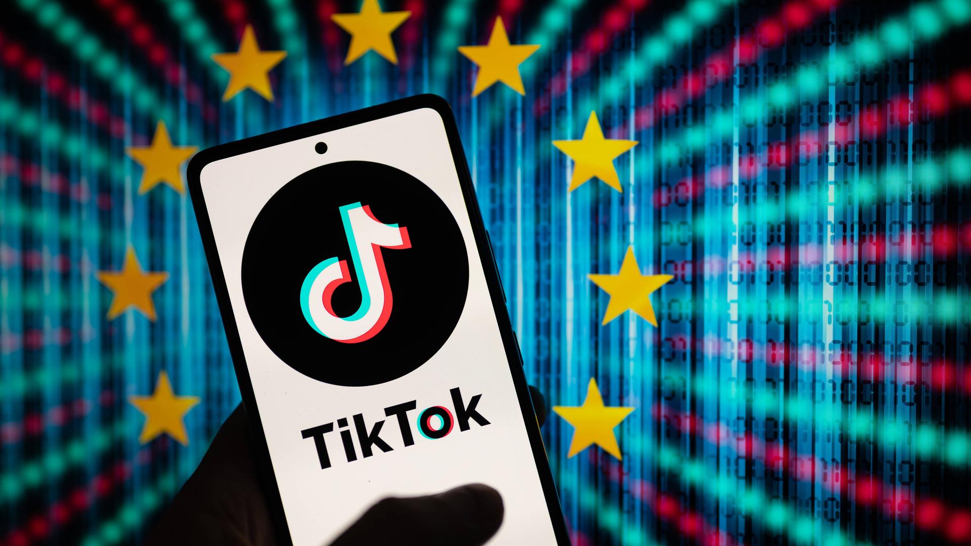 Im Hintergrund sind die EU-Sterne auf bunten Hintergrund zu sehen, im Vordergrund ein Handybildschirm mit TikTok-Logo.