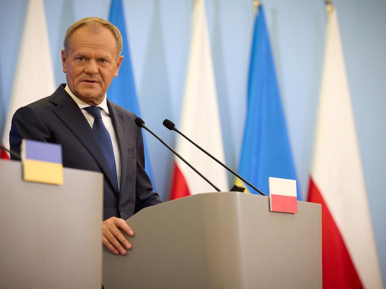 Ein Mann steht an einem Redepult und beantwortet Fragen. Er trägt einen Anzug. Es ist der polnische Premierminister Donald Tusk.