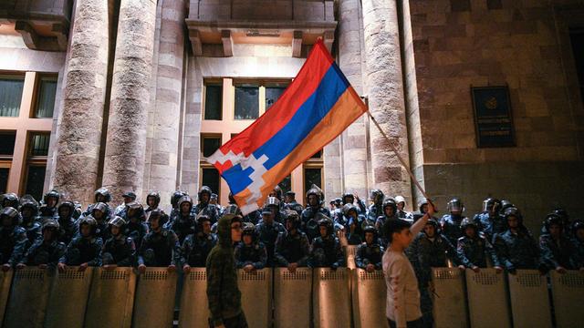 Proteste in Jeriwan, der Hauptstadt von Armenien, zwei Männer tragen eine Fahne, eine Truppe von Soldaten sichert den Regierungspalast, 22. September 2023