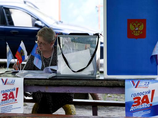 Eine Wahlhelferin neben einer Wahlkabine in Donezk (Ukraine).