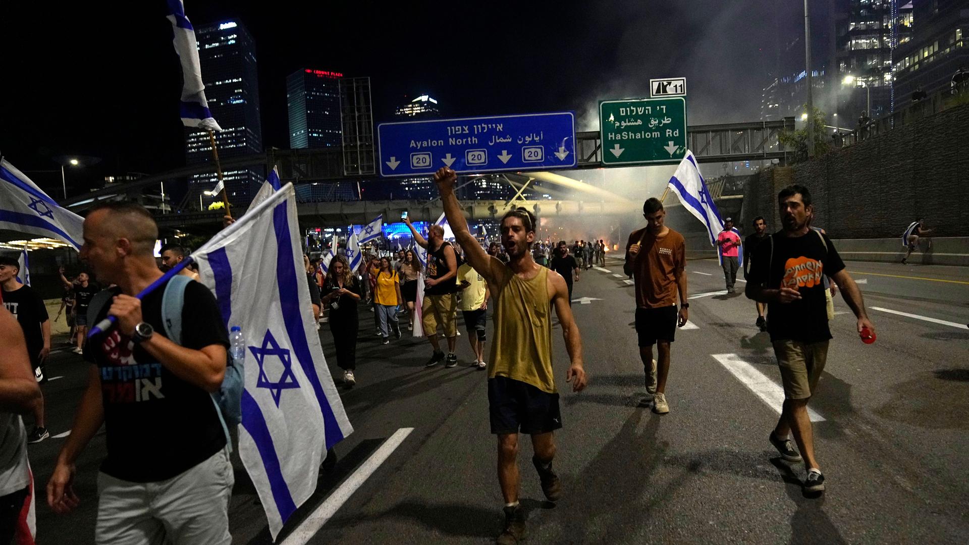 Demontranten laufen in Tel Aviv mit Fahnen auf der Hauptautobahn. Demontranten laufen in Tel Aviv mit Fahnen auf der Hauptautobahn.