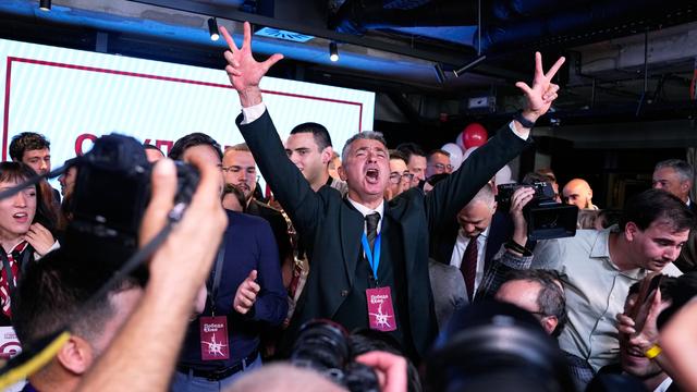 Ilija Srdanovic steht nach der Wahl zwischen Anhängern und Journalisten und feiert den Sieg, er zeigt mit beiden Händen den Drei-Finger-Gruß.