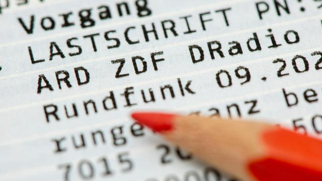 Ein Rotstift liegt auf einem Kontoauszug mit der Lastschrift für den Rundfunkbeitrag für den öffentlich-rechtlichen Rundfunk ARD, ZDF und Deutschlandradio (Symbolbild)