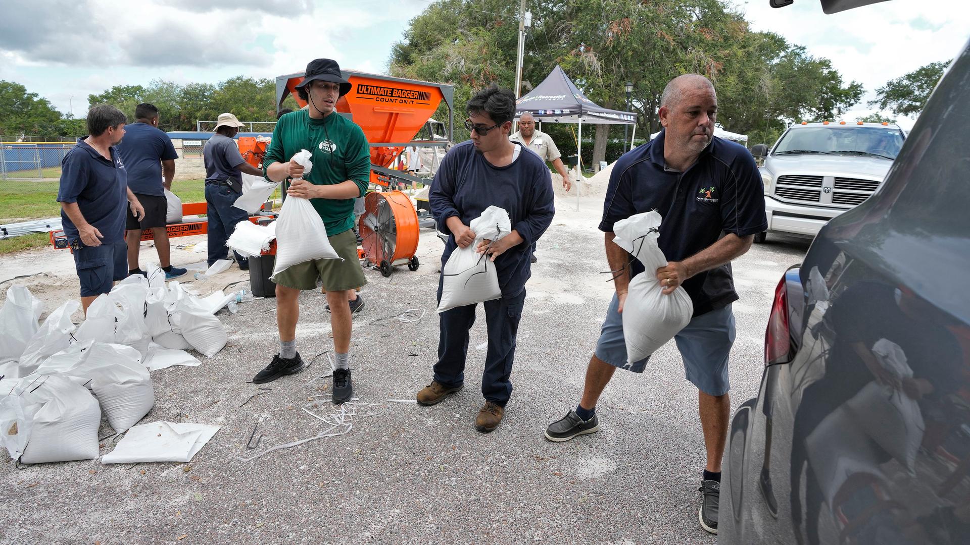 USA, Tampa: Mitarbeiter der Park- und Freizeitbehörde von Tampa helfen Anwohnern beim Verladen von Sandsäcken.