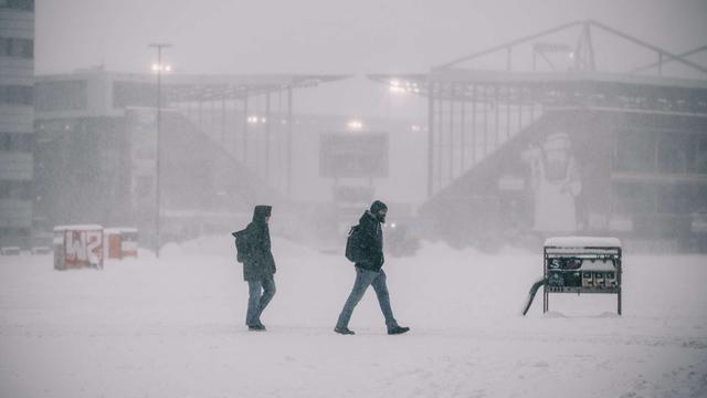 Menschen gehen durch einen Schnee-Sturm.