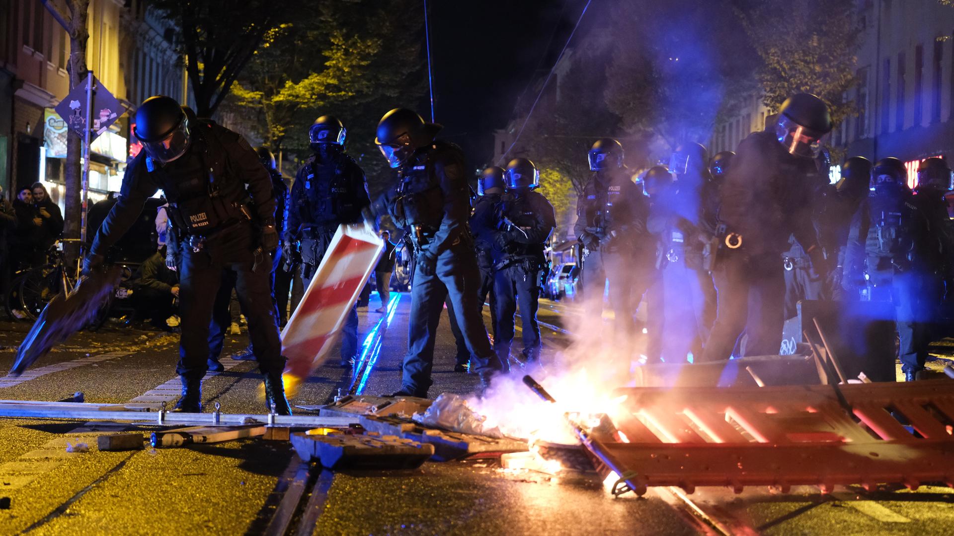 Polizisten räumen brennende Gegenstände von einer Fahrbahn. Polizisten räumen brennende Gegenstände von einer Fahrbahn.