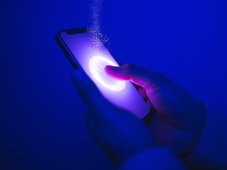 Ein Finger drückt auf einen Smartphone-Bildschirm, es funkelt und blitzt an der Stelle.