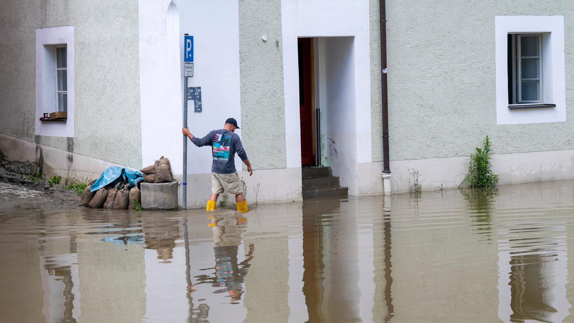 Ein Mann in Gummistiefeln stapft in der Passauer Altstadt durchs Hochwasser.