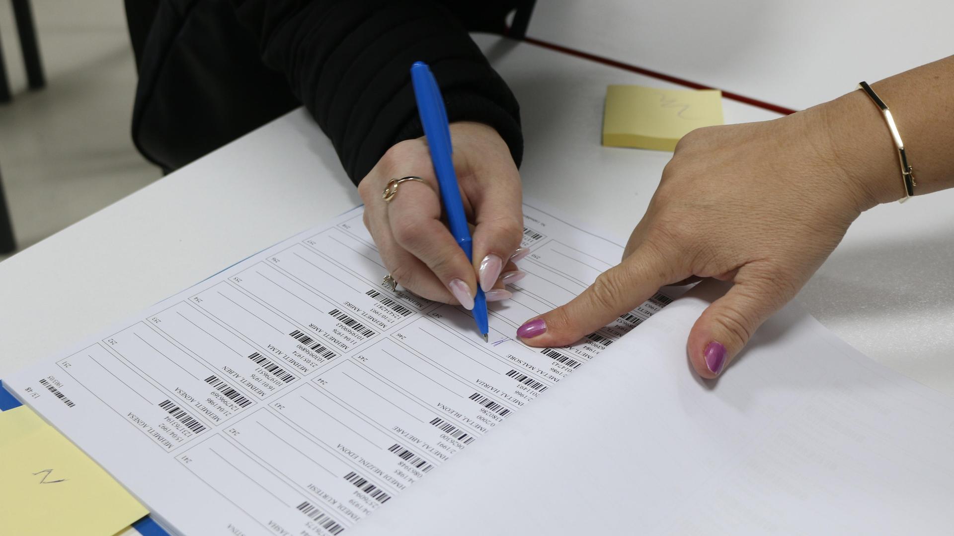 Eine Frau füllt in einem Wahllokal in Pristina, der Hauptstadt des Kosovo, einen Wahlzettel für die Parlamentswahl aus. 