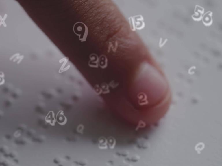 Finger eines Kindes, das Brailleschrift liest. Darüber sind Buchstaben und Zahlen eingeblendet, die verdeutlichen sollen, was das Kind gerade liest.