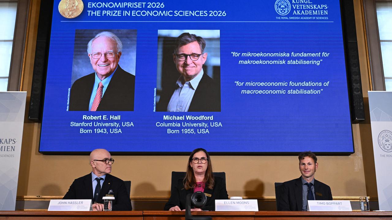 Das Nobelpreiskommitee gibt die beiden Gewinner für den Wirtschaftsnobelpreis an, die auf einem Bildschirm über ihnen mit Bild zu sehen sind.