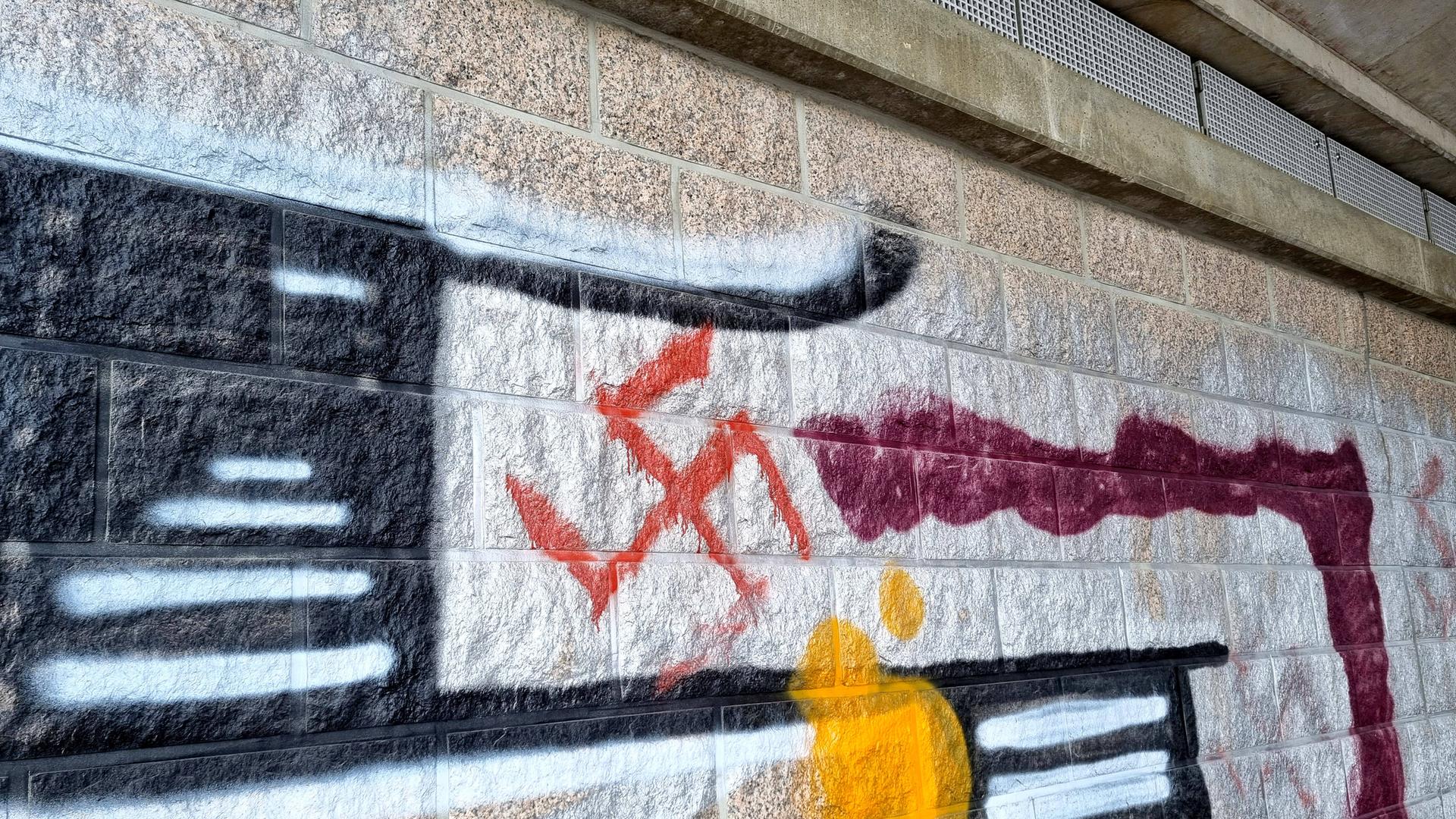 Rote Hakenkreuz-Schmiererei an einer mit Graffitis besprühten Wand.