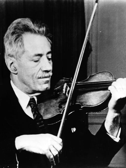 Die Schwarzweiß-Fotografie von ungefähr 1935 zeigt Fritz Kreisler in Anzug und Krawatte beim Spielen seiner Violine.